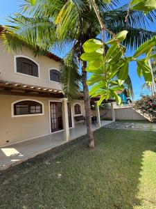 a house with a palm tree in front of it at Casa Becker - Praia Seca in Araruama