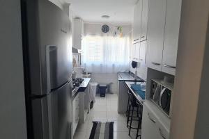a kitchen with white cabinets and a stainless steel refrigerator at Pensado por um turista, pra você in Serra Negra