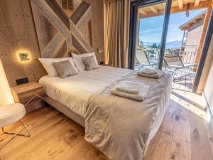 a bedroom with a large bed with a large window at Appartement neuf avec terrasse, SPA et parking inclus - 6 pers - FR-1-352-103 in Arc 1800 +28 photos