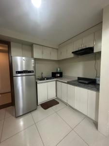 a kitchen with white cabinets and a stainless steel refrigerator at Jojies Crib Horizons101 2bedrooms in Cebu City +64 photos