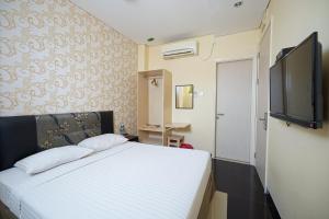 una camera da letto con un letto e una TV a schermo piatto di Multi 88 Syariah a Giacarta Altre 35 foto