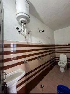 a bathroom with a sink and a toilet with stripes at mayur homestay in Ukhimath