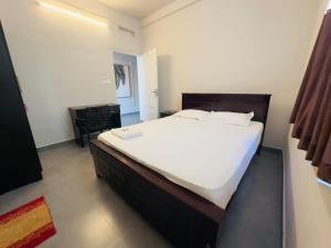 a bedroom with a large white bed and a chair at Town Residency in Kannur