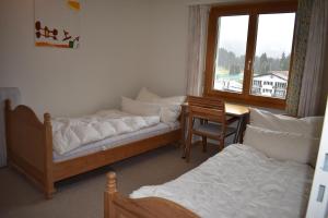 a room with two beds and a desk and a window at Rhodania A 3004 Sr in Lenzerheide +9 photos