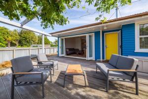 a deck with chairs and a table and a house at Little Blue Bach in Martinborough 