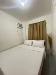 ein weißes Bett in einem Zimmer mit Fenster in der Unterkunft Tuyu Homestay in General Luna