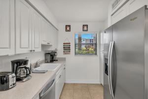 a kitchen with white cabinets and a stainless steel refrigerator at Prime Location I 2 Bed Setup Directly Across Street From South Beach Access in Henry Key +18 photos