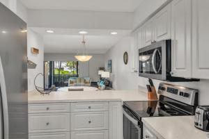 a kitchen with white cabinets and a living room at Prime Location I 2 Bed Setup Directly Across Street From South Beach Access in Henry Key