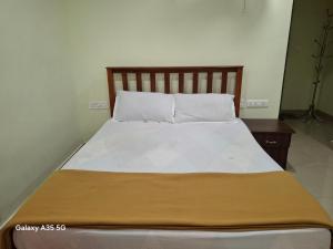 uma cama com lençóis brancos e uma cabeceira em madeira em NIDRA HOMESTAY em Anachal