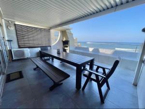 a table and a bench in a room with the ocean at VayKZN Umdloti in Umdloti
