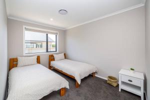 two beds in a room with a window at Stonehenge Retreat in Martinborough +24 photos