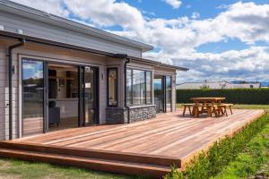 a wooden deck with a picnic table on a house at Stonehenge Retreat in Martinborough