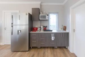 a kitchen with a stainless steel refrigerator and a sink at SandDollar - Self Catering Seaside Getaway in Cape St Francis