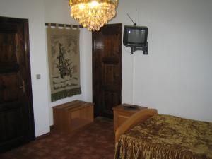 Arbanassi Hotel في ارباناسي: غرفة نوم بسرير وتلفزيون وثريا