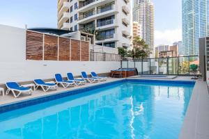a swimming pool with chairs and a building at Oceanfront 24th Floor 1 Bedroom Retreat with Stunning Views & Free Parking in Gold Coast