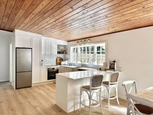 a kitchen with white cabinets and a wooden ceiling at Kauri Lodge in Taupaki