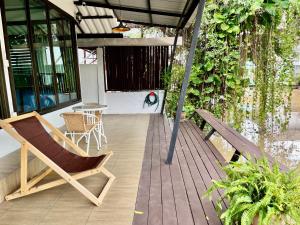 a wooden deck with a chair and a table at Kirin Riverside Homestay with AC, WiFi in Bangkok in Rat Burana