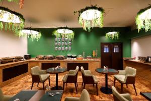 a restaurant with tables and chairs and a green wall at Quality Inn City Centre Varanasi in Varanasi