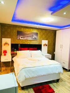 a bedroom with a large white bed with a painting on the wall at Debreeze guest lodge in Malelane