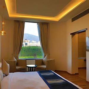 瑞诗凯诗Hotel Natraj Rishikesh的一间带床和大窗户的酒店房间