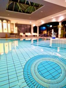 a large swimming pool with a blue tile floor at Apartments C'EST LA SEA - Whirlpool-Suite oder Dachterrassen-Suite in Neusiedl am See