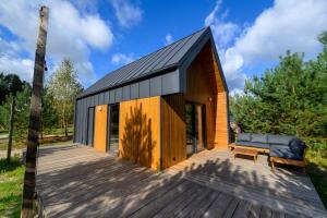 a small house with a black roof on a wooden deck at Grotów 2e in Drezdenko