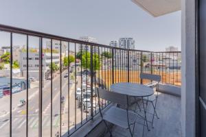 a balcony with a table and chairs and a view of a city at Blueground Florentine, City view in Tel Aviv