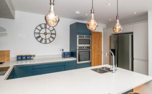 a kitchen with blue cabinets and a clock on the wall at Romille Cottage in Skipton +8 photos
