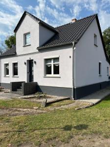 a white house with a black roof at Landhaus-Ferienwohnung am Fluss in Plattenburg