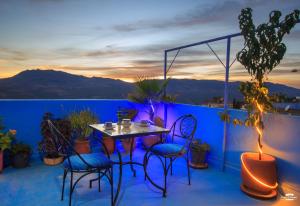 a patio with a table and chairs on a balcony at Casa Voyager 'secret garden terrace' in Chefchaouen