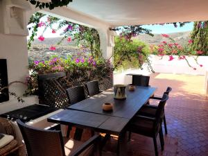 a wooden table and chairs on a patio with flowers at Casa La Cúpula in Agua Amarga