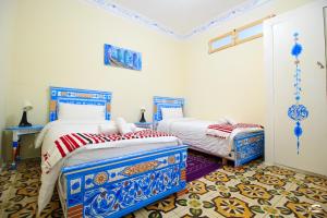 two beds in a room with blue and white at Casa Voyager 'secret garden terrace' in Chefchaouen
