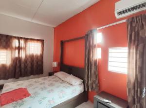 una camera da letto con una parete arancione, un letto e una finestra di Balinese Villa at Seri Kembangan12 to15 pax a Seri Kembangan
