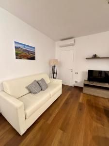 Una sala de estar con un sofá blanco y un televisor. en Dimora Rosé, en Alba