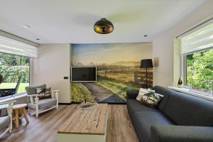 a living room with a couch and a tv at Comfortabel 2- persoons vakantiehuis nabij bos in Drenthe in Schoonoord