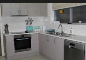 a white kitchen with a sink and a stove at Gilbert rise in Boolarra