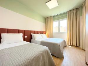 a hotel room with two beds and a window at Cozy Nest Golem in Golem