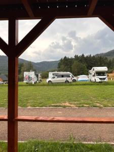 a view of a field with two rvs and a car at Góry Stołowe Camp - Rodzinne pole biwakowe, Kampery, Przyczepy, Namioty in Radków