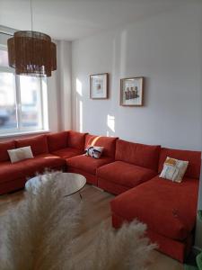 a living room with a red couch and a table at Maison de vacances près de la digue et plage in Dunkerque