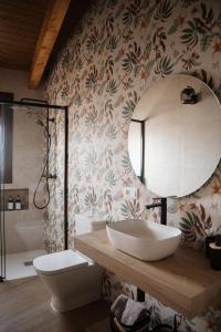 a bathroom with a sink and a toilet and a mirror at El gallinero de la abuela Claudia in Aldea de Trujillo