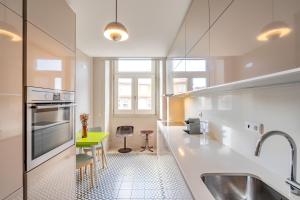 a kitchen with white counters and a green table at VIVA Aliados Spacious & Bright Flat in Porto