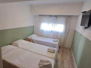 two beds in a small room with a window at Cala Hotel MDP in Mar del Plata