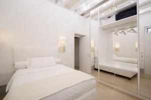 a white bedroom with a white bed and a mirror at Lemon House in Venice