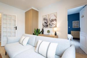 a living room with a white couch and a bedroom at Tropical Escape near city center Fiber Netflix in Montluçon