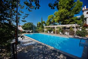 a large swimming pool with chairs and tables at Kamelia Villas in Votsi