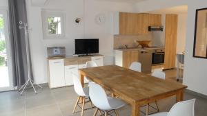 a kitchen with a wooden table and white chairs at Bas de villa indépendant prestations haut de gamme in Vallauris