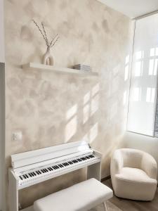 a white piano and a chair in a room at Le Petit Cocon - Pause douceur in Cambrai