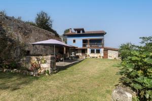 une grande maison avec un parasol dans une cour dans l'établissement La Casona de Abajo, à Avalle 