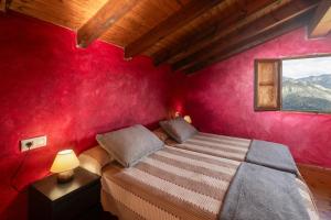 une chambre avec un lit et un mur rouge dans l'établissement La Casona de Abajo, à Avalle 