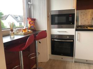 eine Küche mit einer Theke, einer Mikrowelle und einem Herd in der Unterkunft Victorian Flat in Bonhill